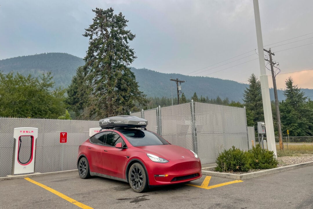 a red tesla is parked near a charging station in a parking lot