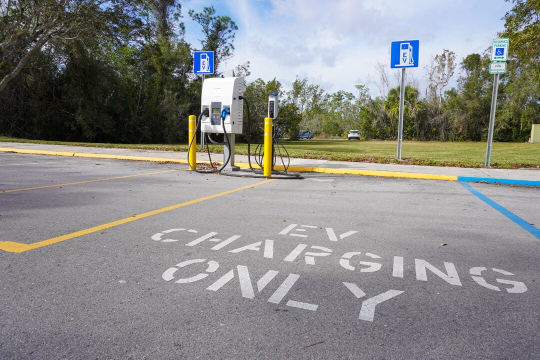 a parking lot with EV chargers and painted letters on the ground that say "EV charging only"