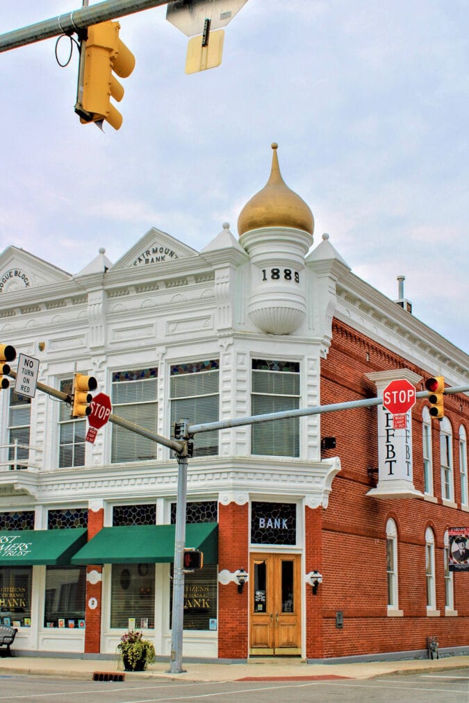 a street corner in a small town with brick buildings and a corner with a gold onion dome that says 1889