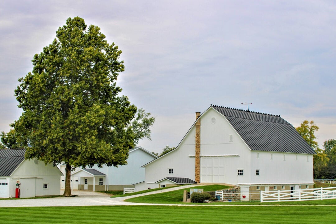 a farm featuring a large white barn and picket fence