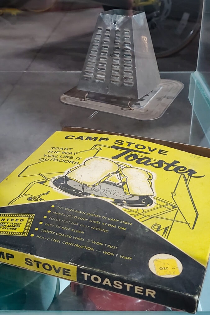 a vintage camp stove toaster and box on display in a museum