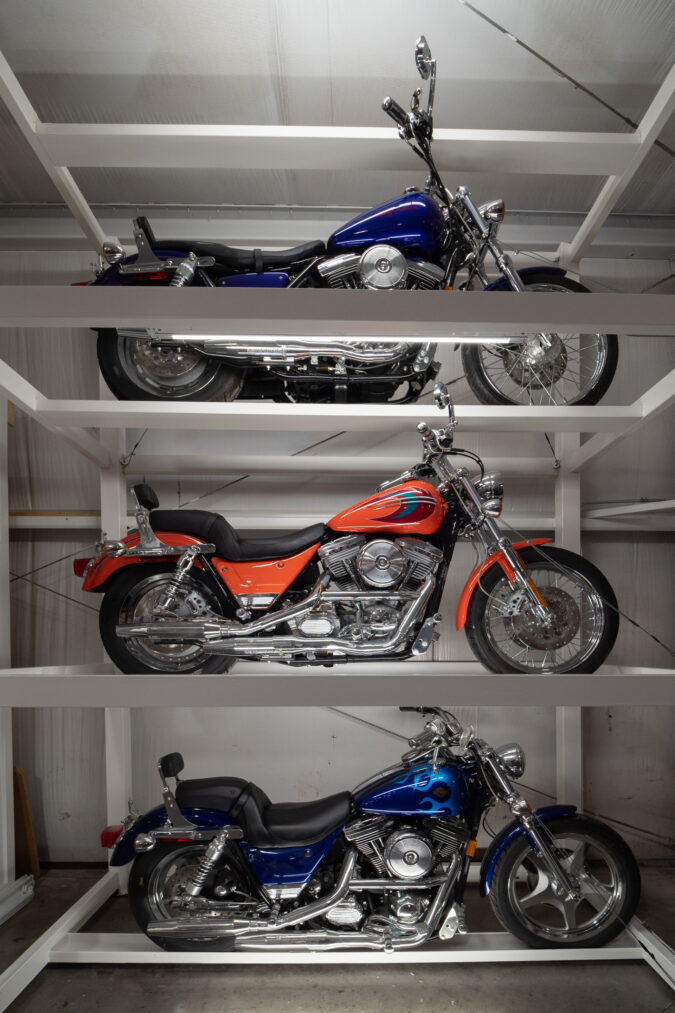 three harley-davidson motorcycles displayed vertically in a museum