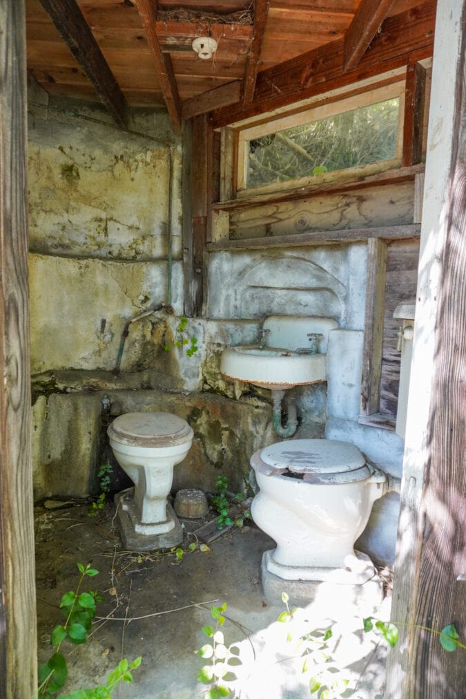 An old outhouse with two toilets and a sink