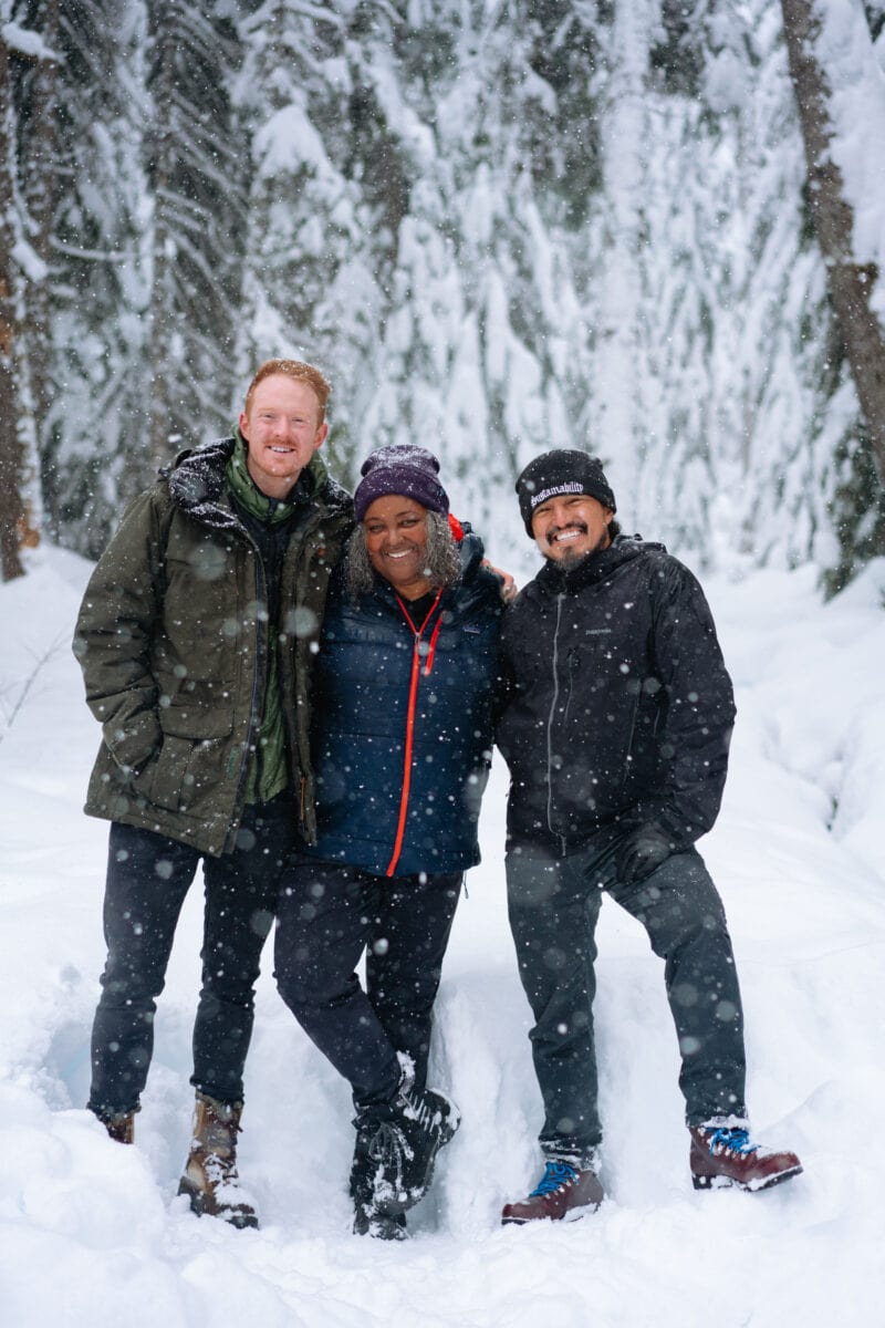 three people pose in the snow