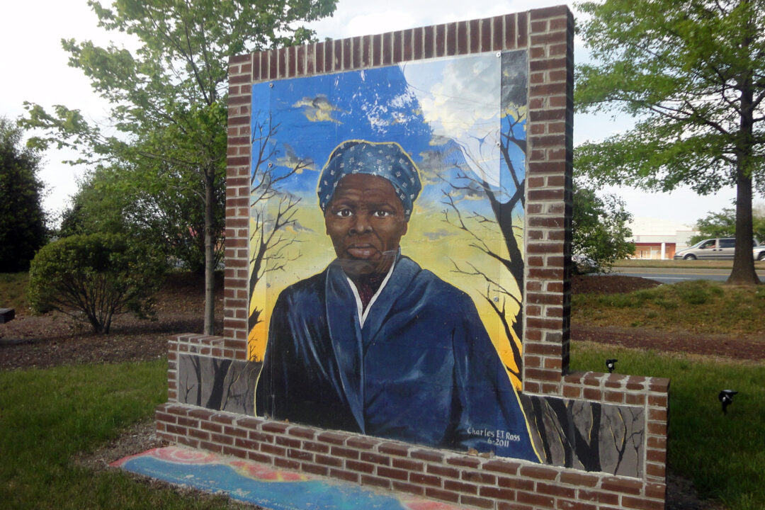 a free-standing mural depicting Harriet Tubman painted on bricks in a garden
