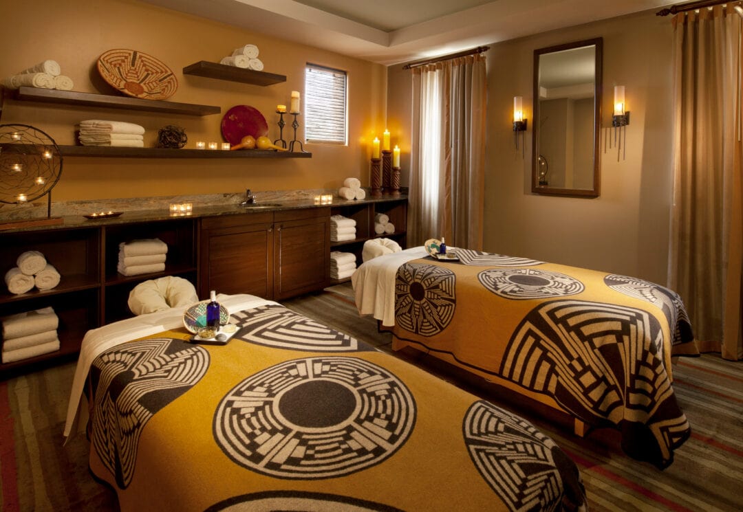 a massage room at a spa with two beds and various candles