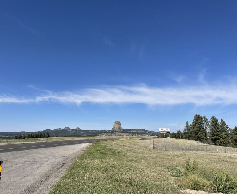Devils Tower rock formation in the distance down an open road.