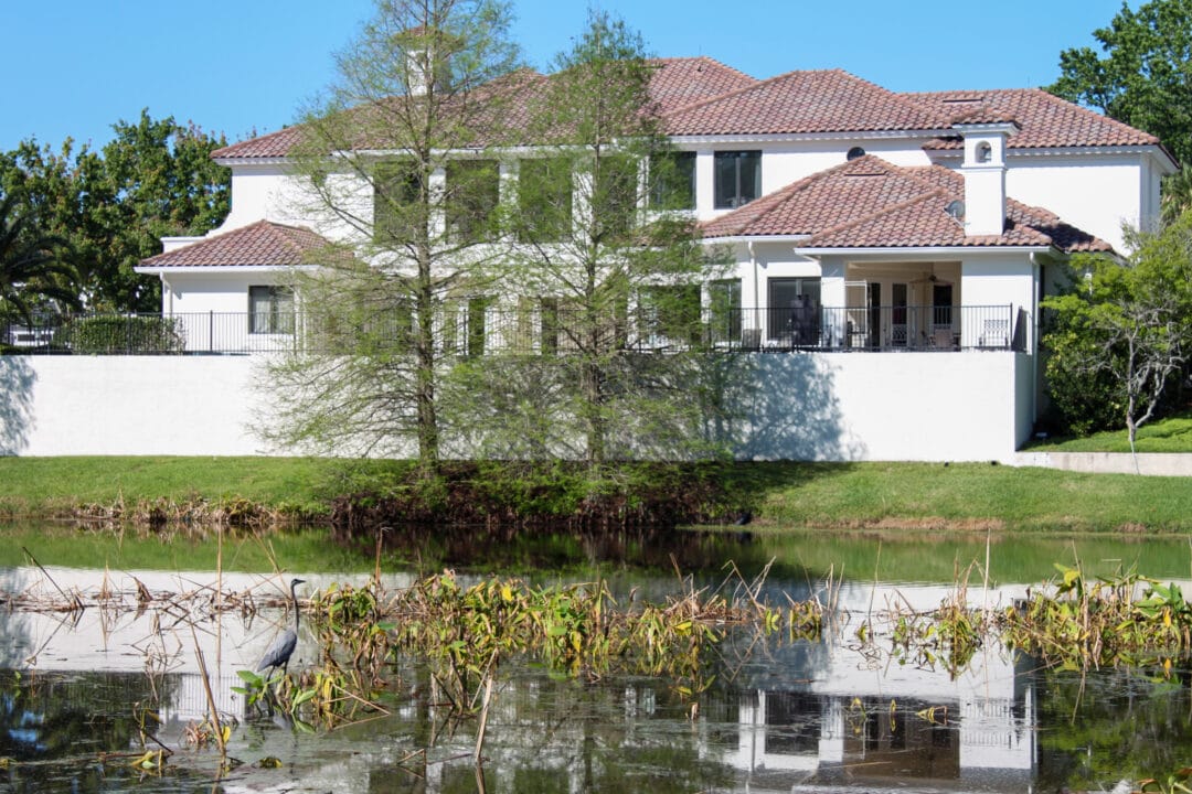 a large spanish style red and white house near water with greenery and blue skies