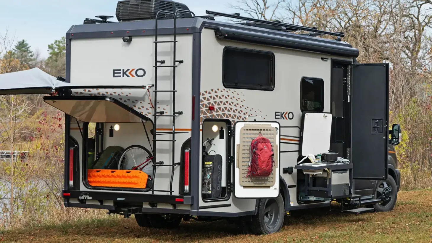 Exterior of a Class B+ RV with storage units open and a ladder going up to the roof