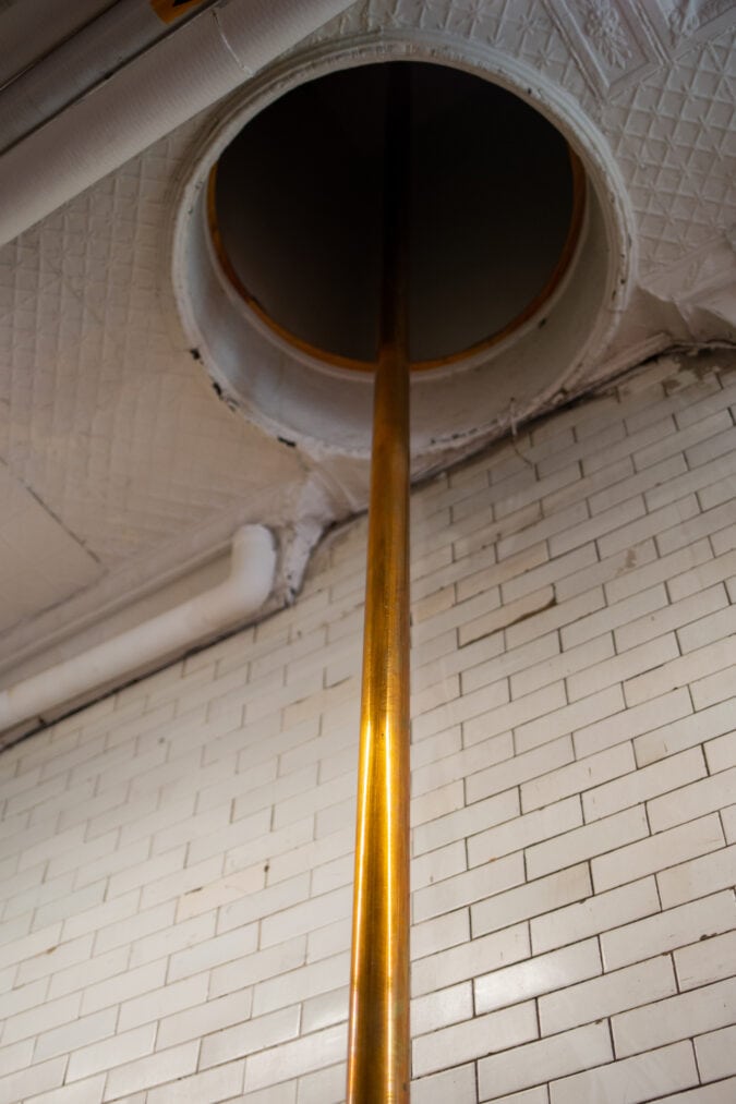 a shiny gold fire pole through a ceiling in a firehouse