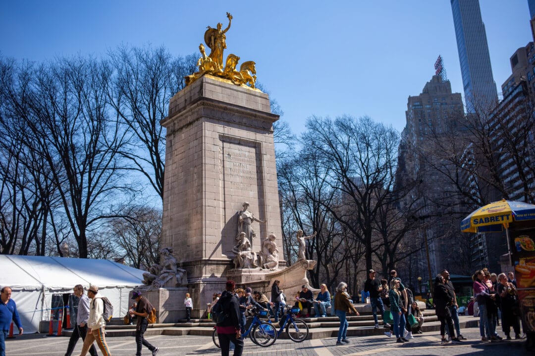 a stone monument on a crowded pedestrian plaza in new york