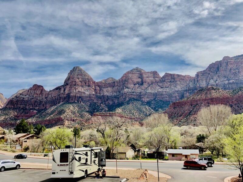 RV parked in a lot at Zion National Park with mountains in the background