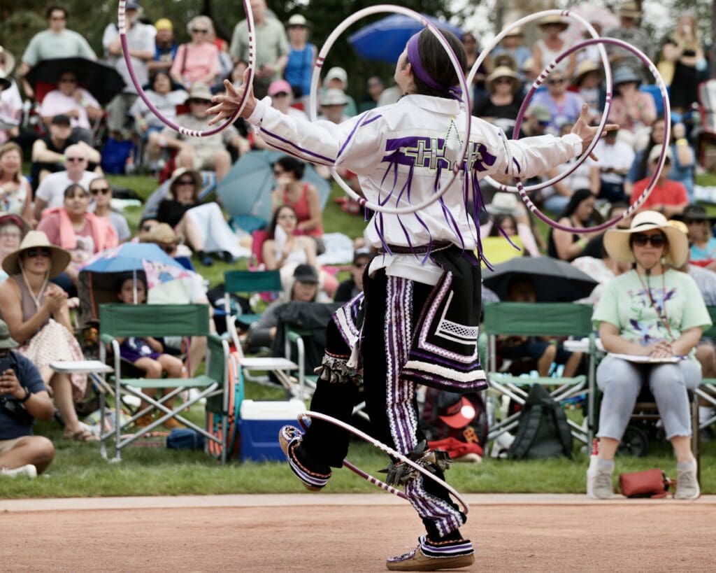 a boy juggles several hoops and dances in front of a crowd