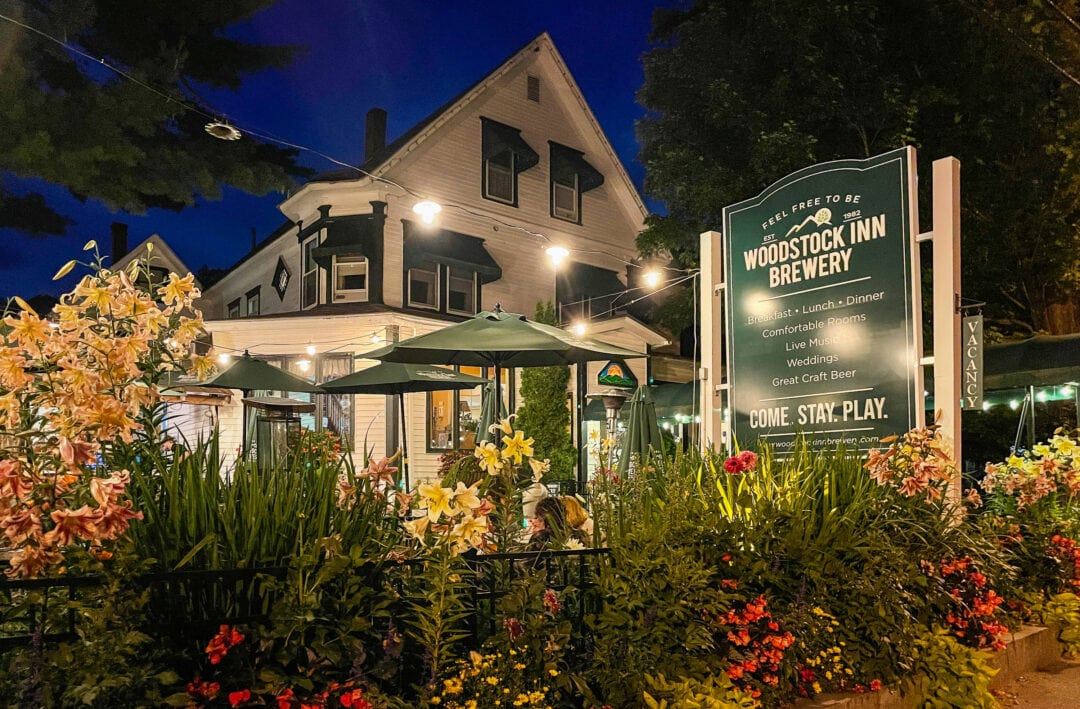 a white and green inn surrounded by colorful flowers at night