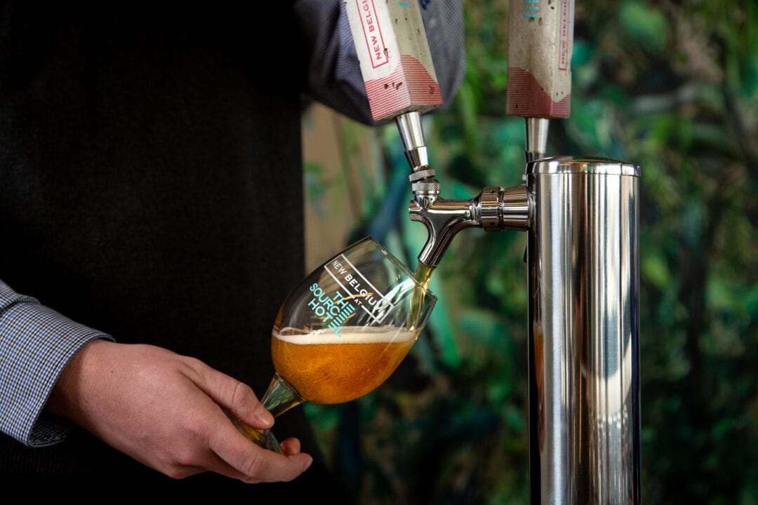 a hand holds a glass and fills it with beer from a tap
