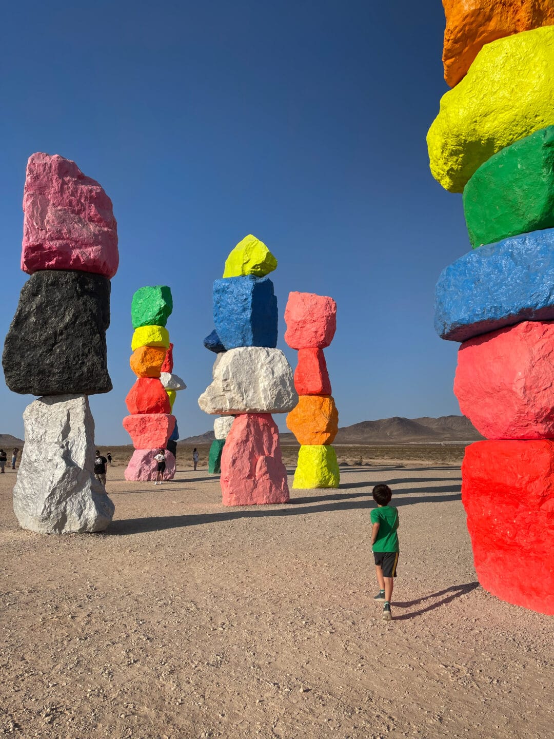 stacks of rocks painted neon colors in the desert against a blue sky