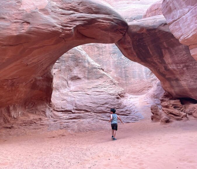 Little boy exploring red rock formations at Arches National Park