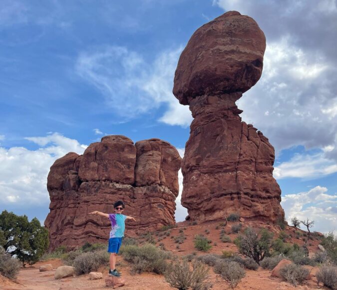 Little boy standing by Balanced Rock in Arches National Park