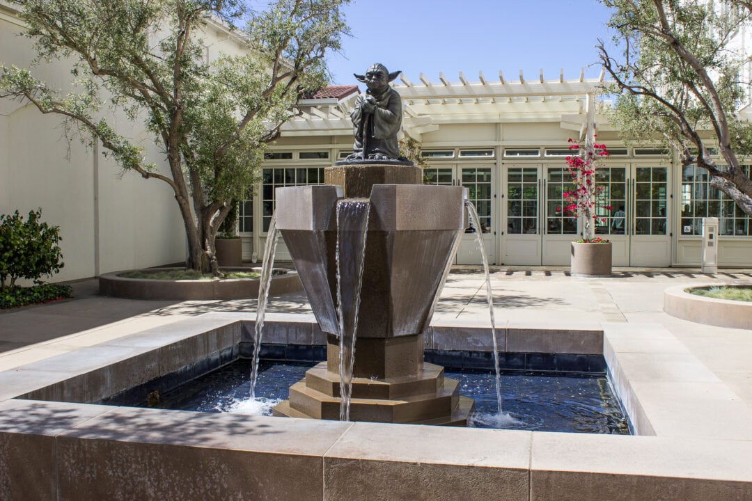 Yoda statue placed atop a fountain outside of a white building