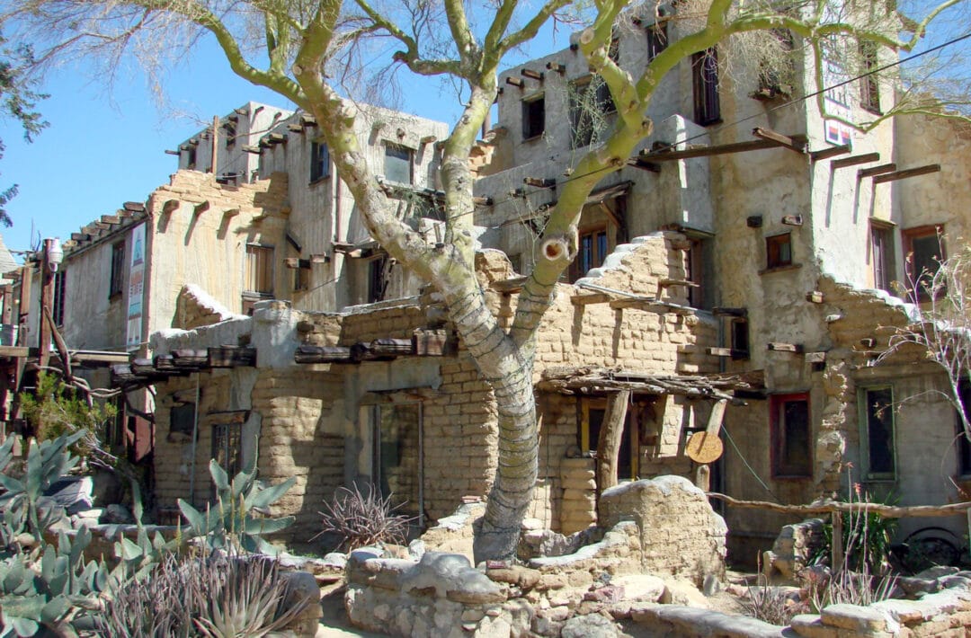 A multi-story pueblo building with lots of nooks and crannies and desert landscaping outside