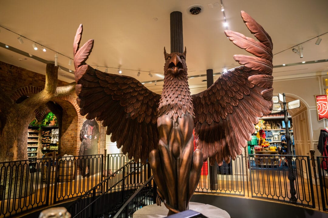 a large statue of a bird looms over a harry potter themed store
