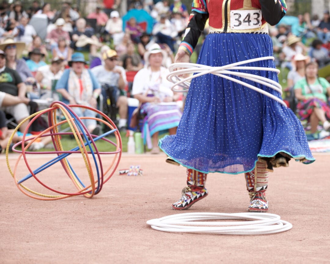 a tangle of colored hoops next to a woman in a blue skirt with white hoops circling her lower half
