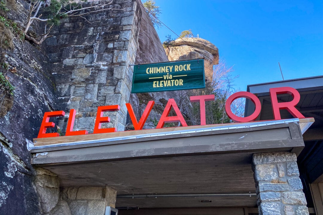the entrance to an elevator spelled out in red letters with a sign that says "chimney rock via elevator"