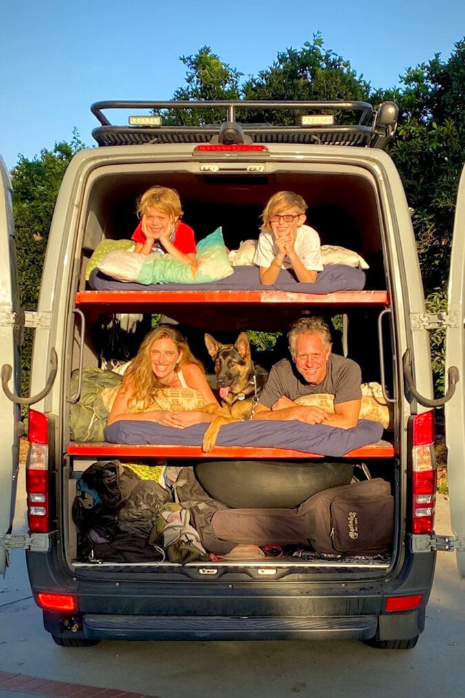 the back of a campervan with four people and a dog stacked inside