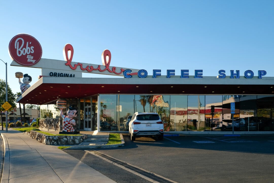 the exterior of bob's big boy broiler coffee shop with a big boy statue out front and a white car in the parking lot