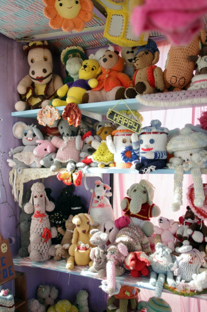 dozens of crocheted animals and figures sit on shelves