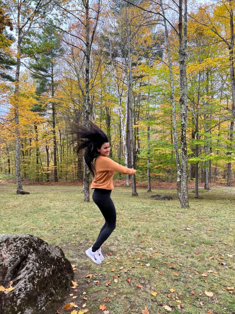 a person jumps outside with a backdrop of yellow fall foliage