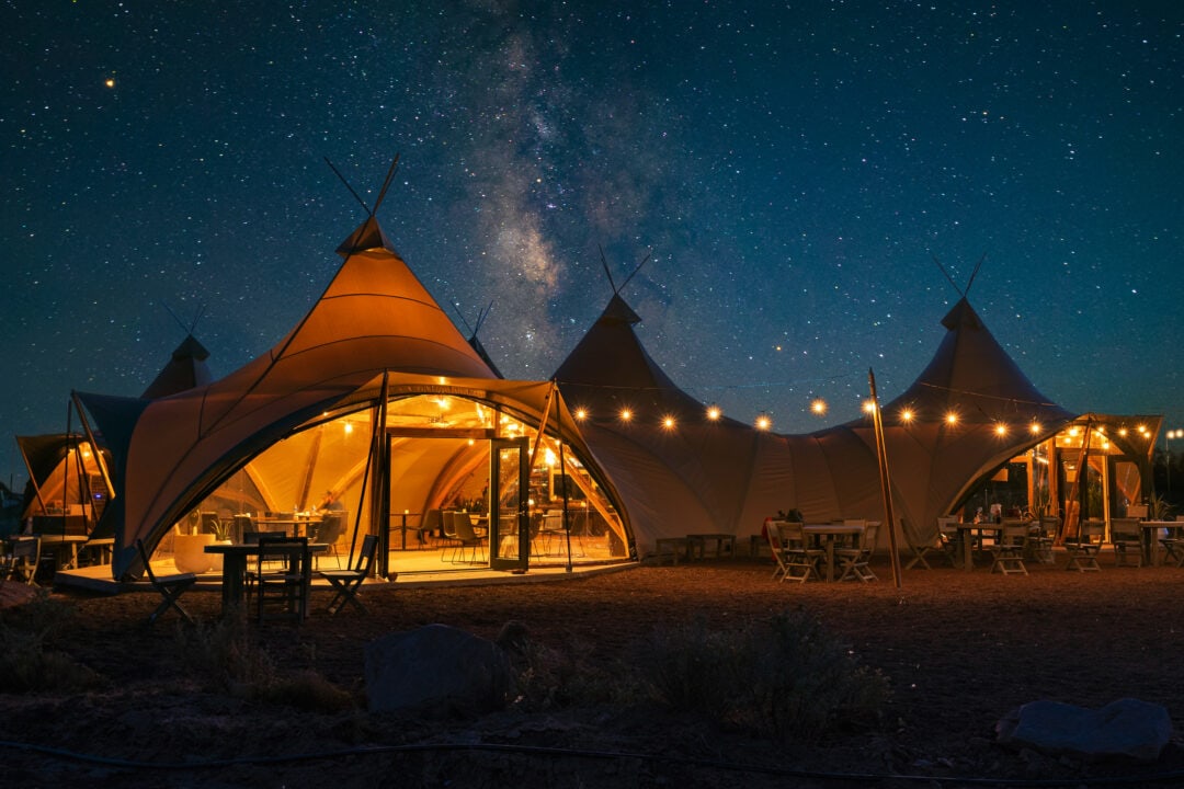 glamping tents lit up at night under a sky full of stars