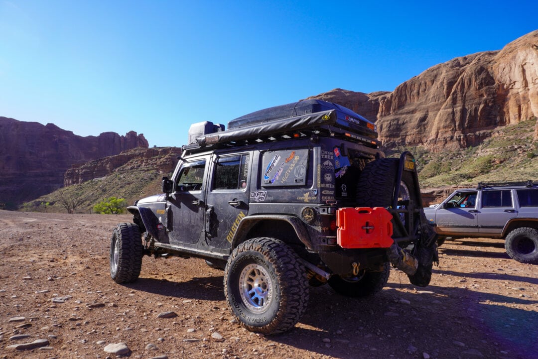 A loaded up overlanding Jeep surrounded by towering red rocks