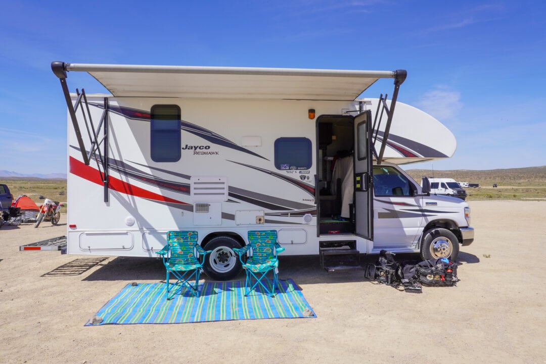 Class C motorhome with two camping chairs in front