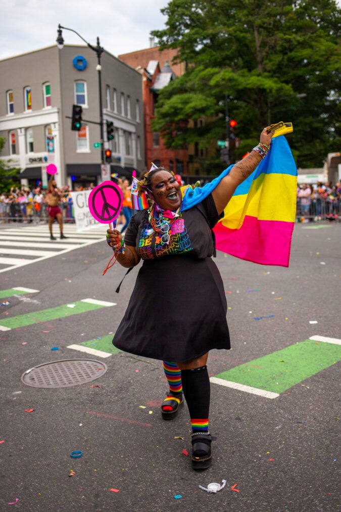 a person wears a pansexual flag and marches in a parade