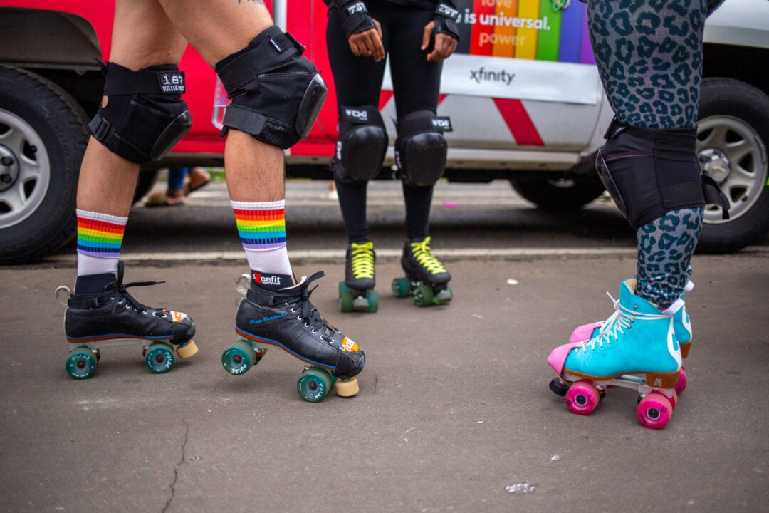 three people stand in colorful rollerskates