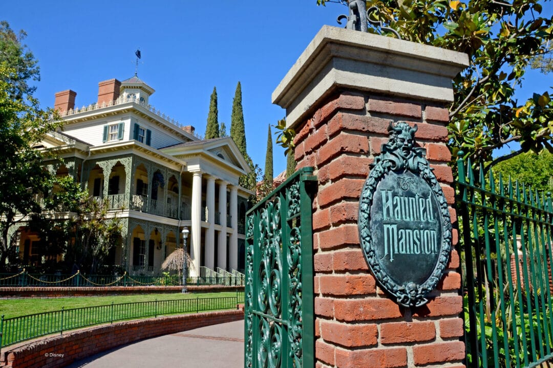 the entrance gate to the haunted mansion in front of a large mansion