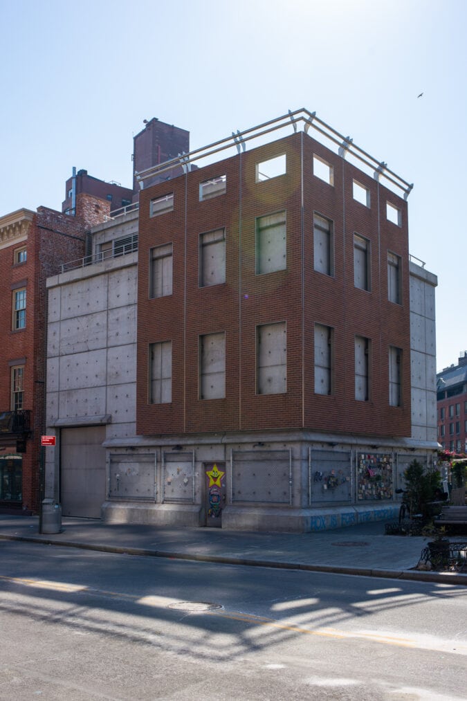 a concrete corner building wrapped in a partial red brick facade