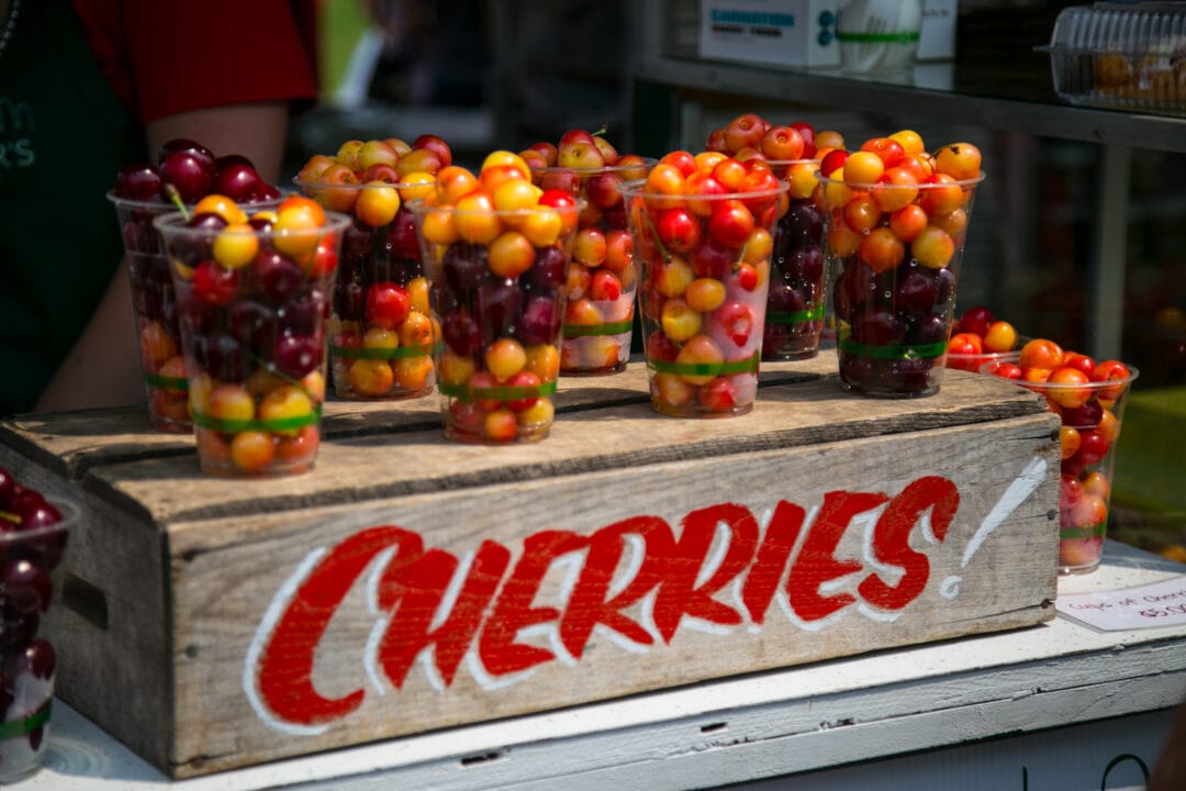 a wooden crate that says cherries with several cups of yellow and red cherries on top