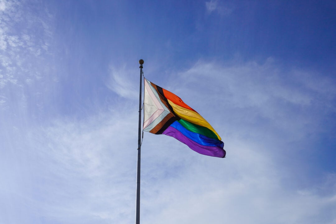 a rainbow pride flag flies in front of a blue sky
