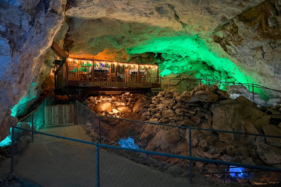 inside of a cave lit with green spotlights and a structure that says "caverns grotto"