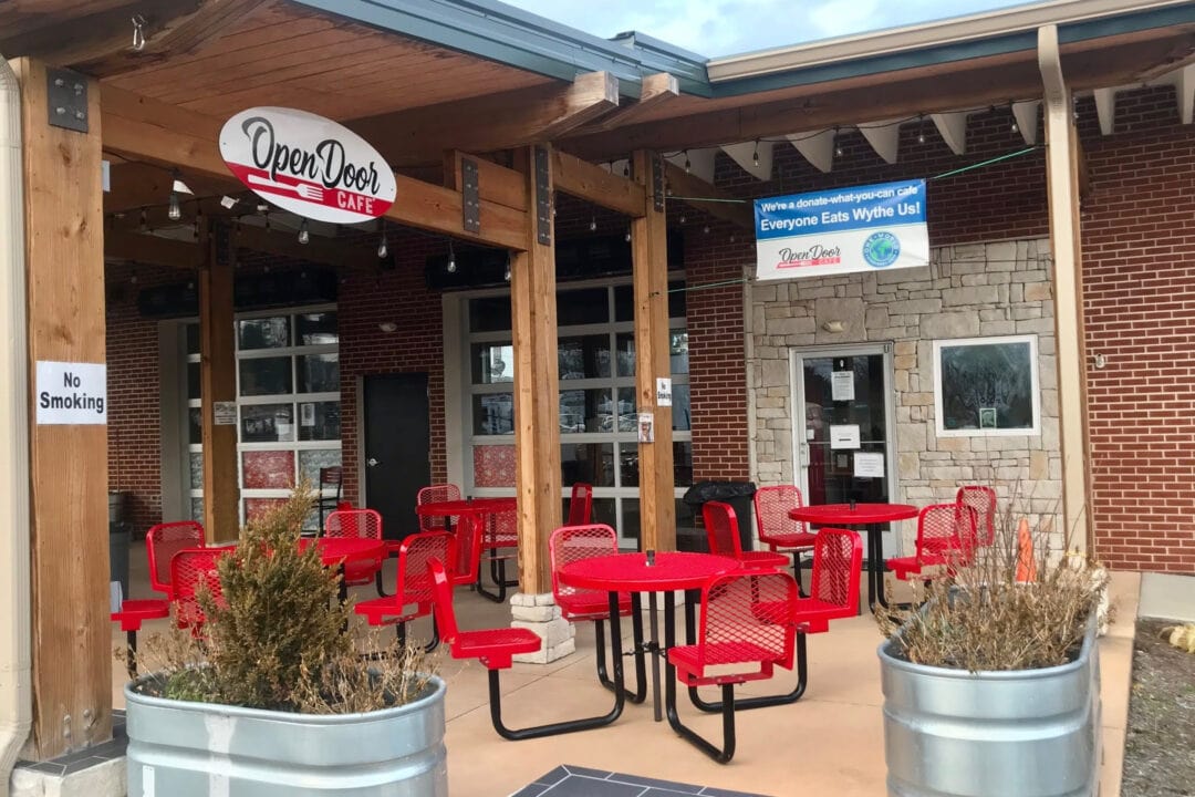 the open door cafe with outdoor seating including several metal red tables and chairs