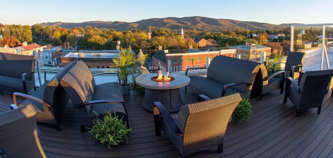 a panoramic view of a rooftop bar with fire pits overlooking the mountains