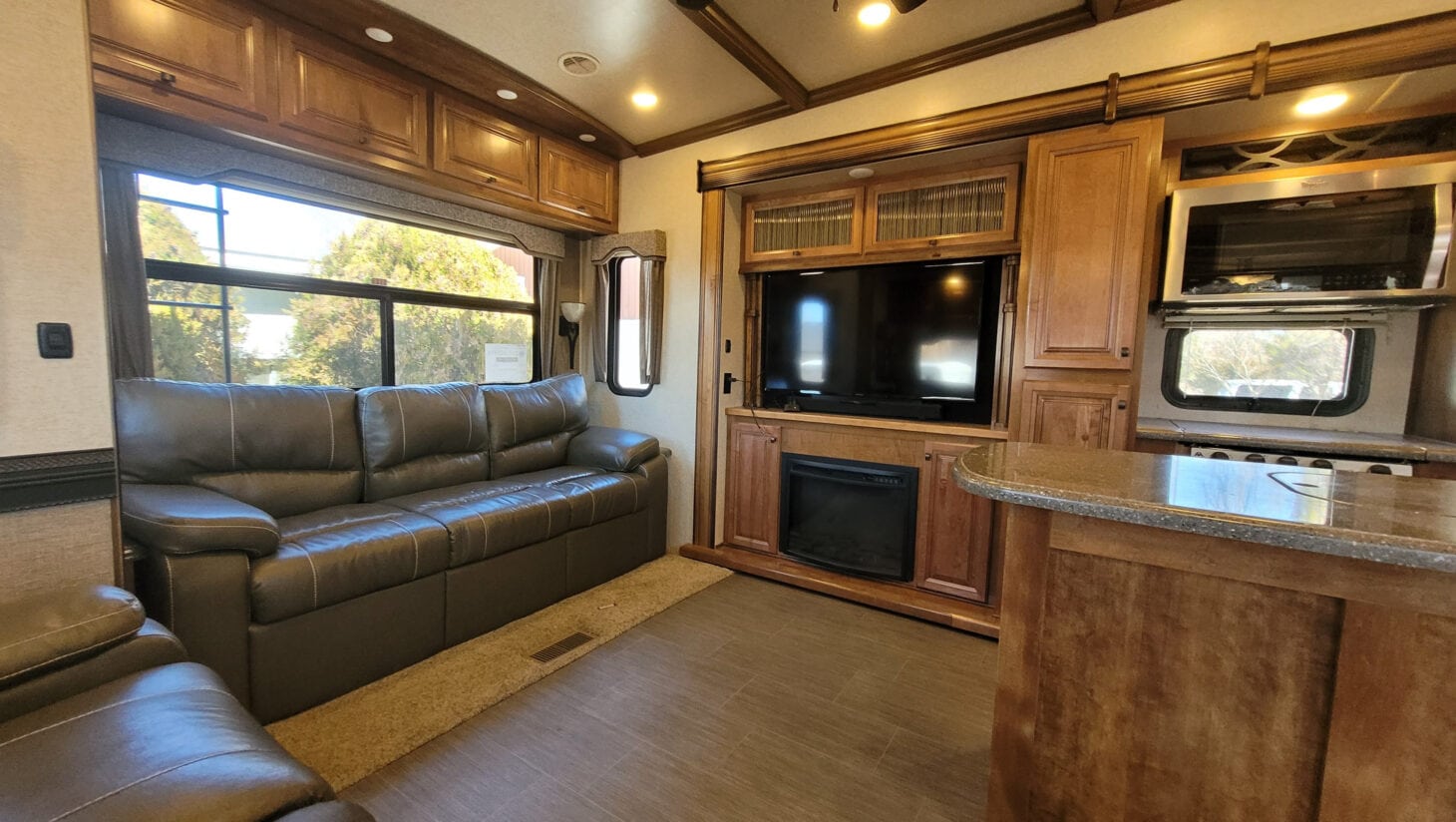 the interior of an RV with a brown leather couch and wooden cabinets