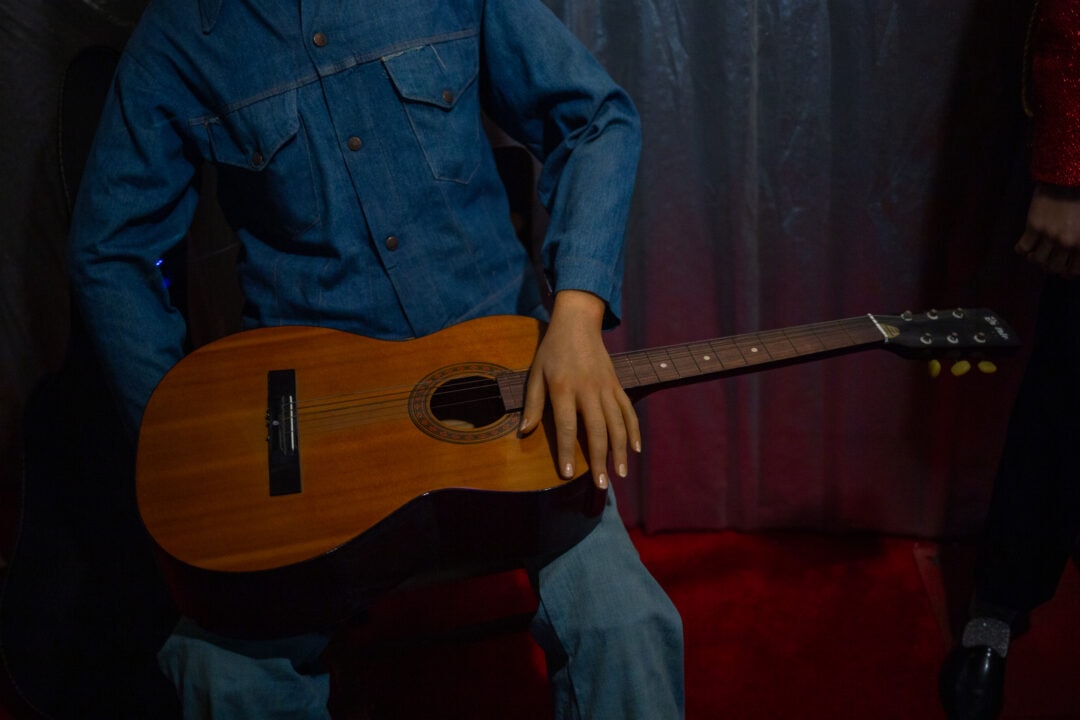 a wax figure holds a guitar