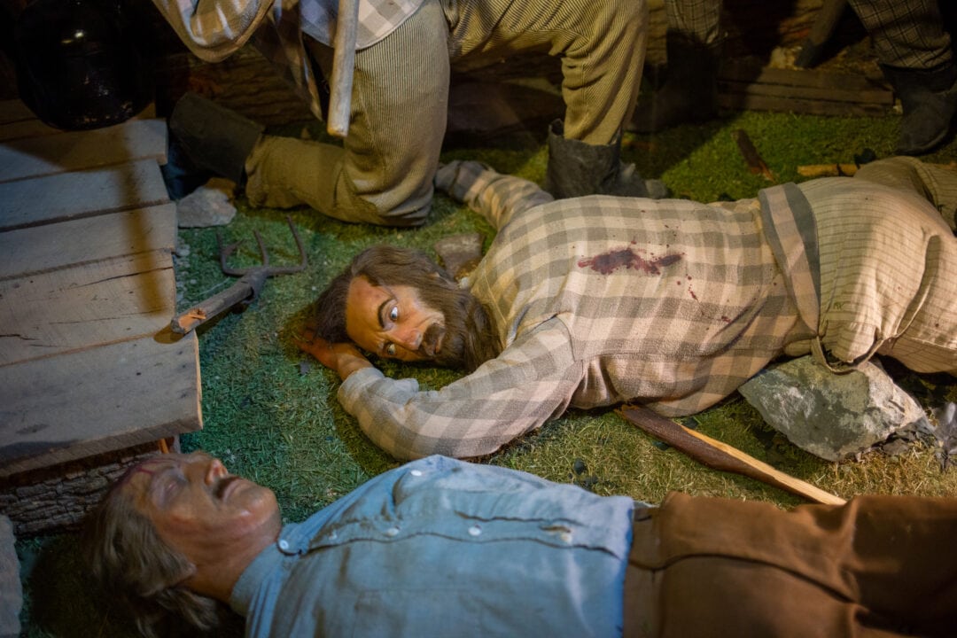 wax figures lay on the ground in a diorama depicting a battle
