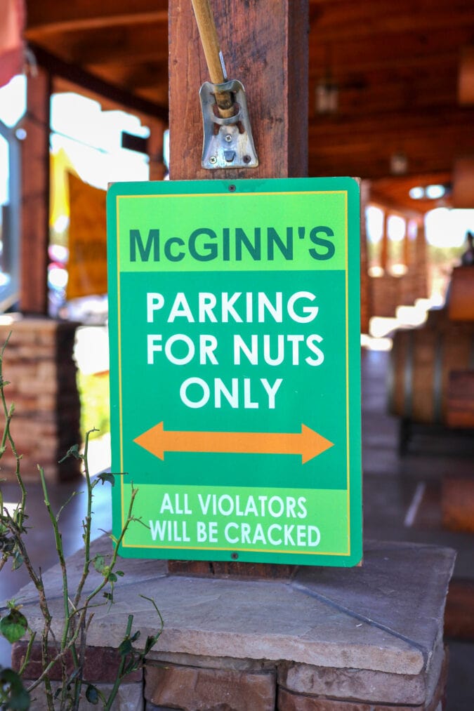 a green and orange sign that says "mcginn's parking for nuts only all violators will be cracked"