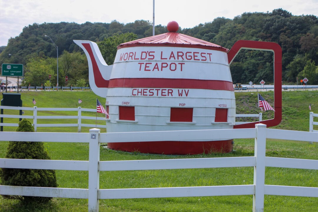 an oversized red and white teapot building surrounded by a white fence