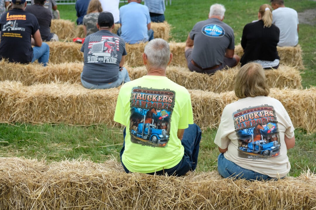 people sit on haystacks wearing shirts for the truckers jamboree