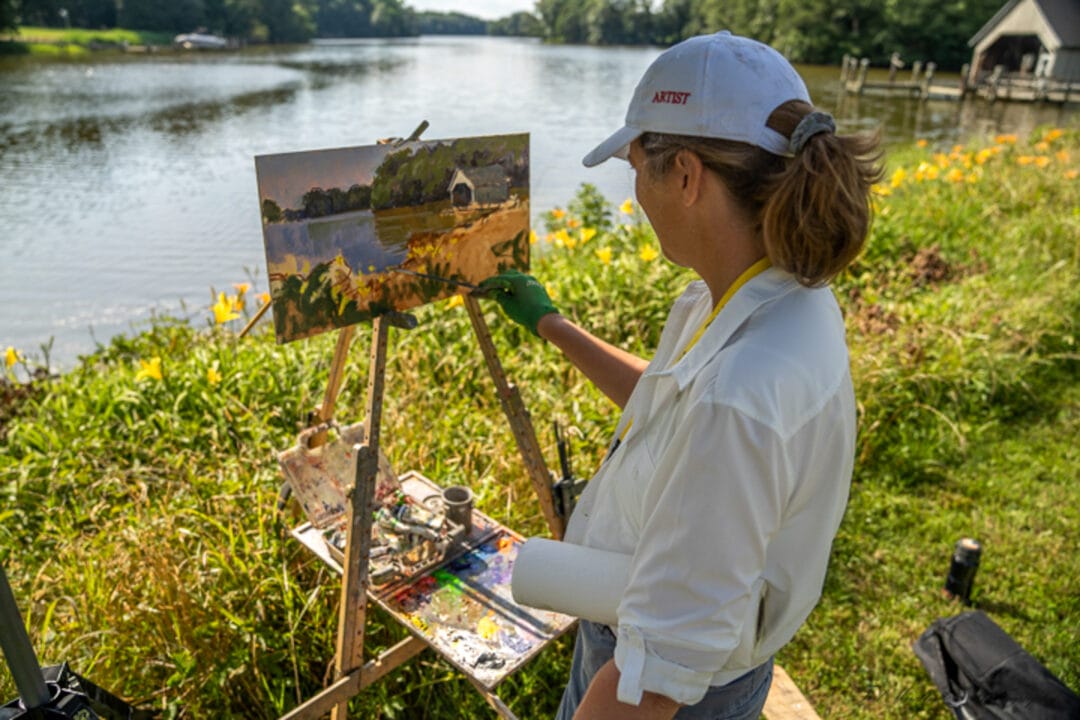 a woman paints an idyllic scene by the water